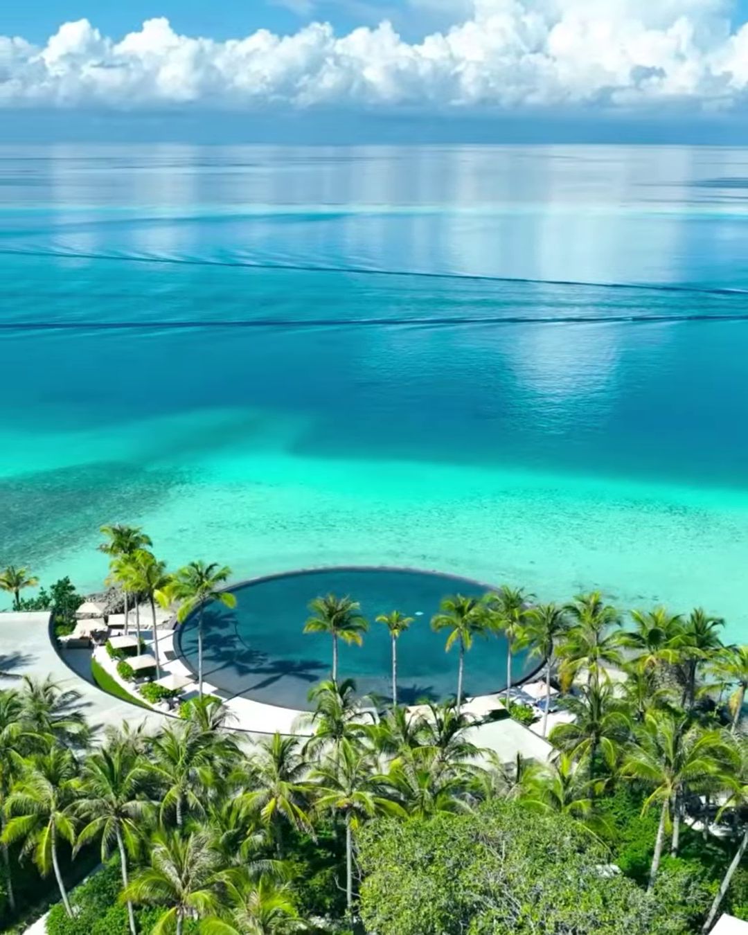 An infinity pool among palms beside a turquoise Maldives lagoon