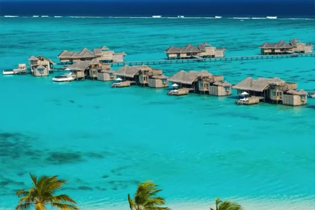 Overwater villas and palm-lined white sand above a turquoise Maldives lagoon